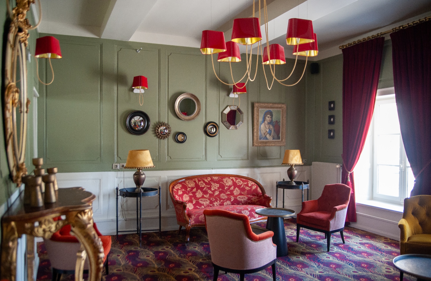 Salon vert d'eau avec boiseries, lustre rouge contemporain et canapé rouge à motifs floraux