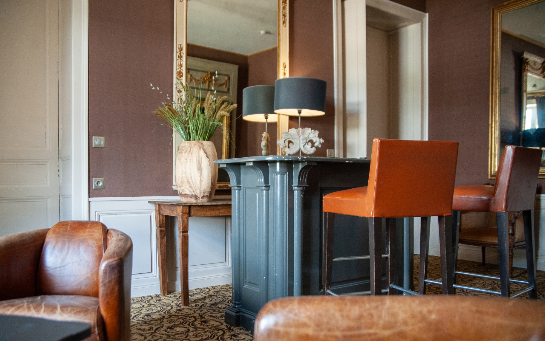 Bar du château avec tabourets en cuir orange et console en bois ancien
