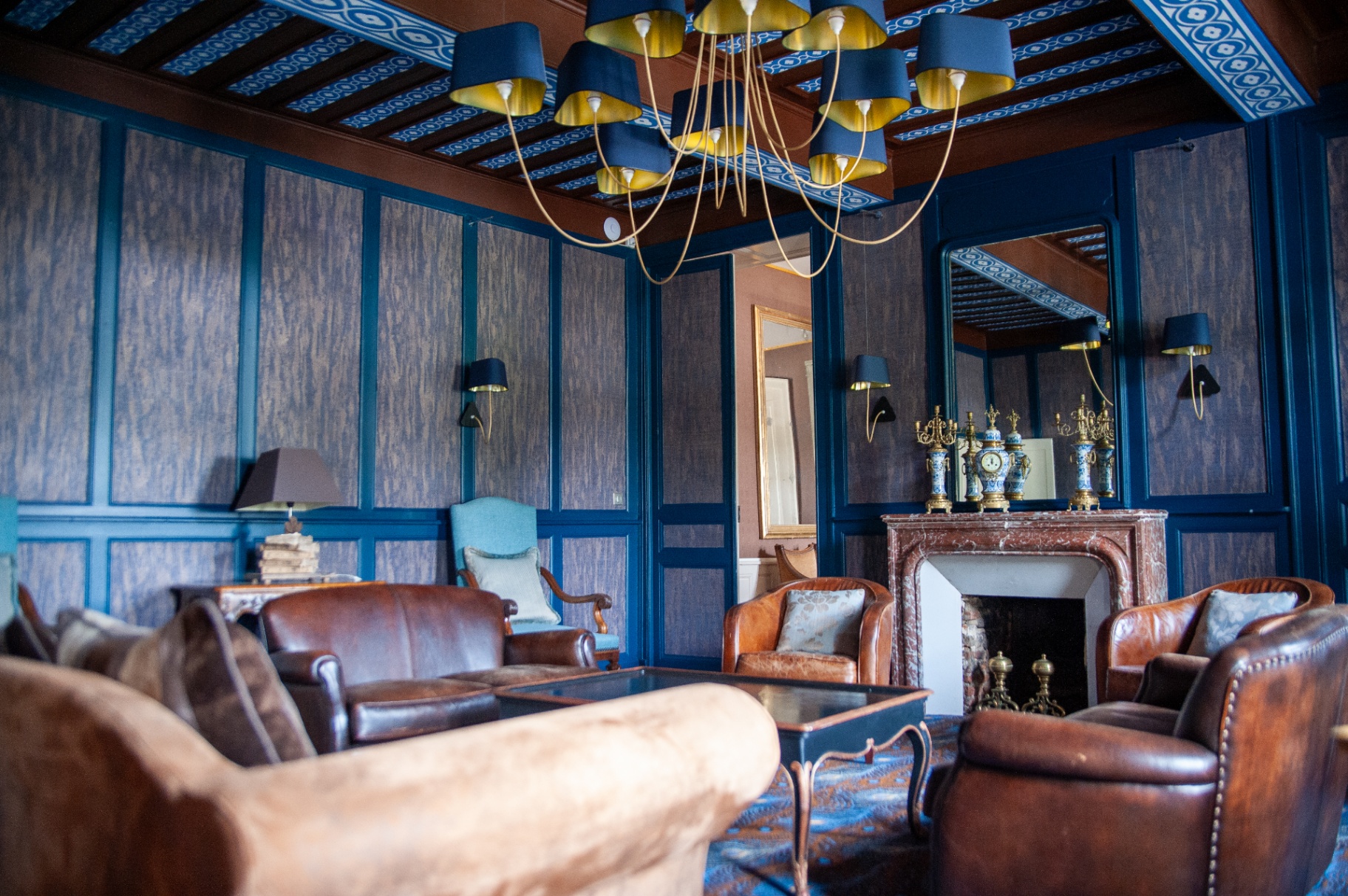 Salon bleu avec cheminée en marbre rouge, fauteuils club et candélabres anciens