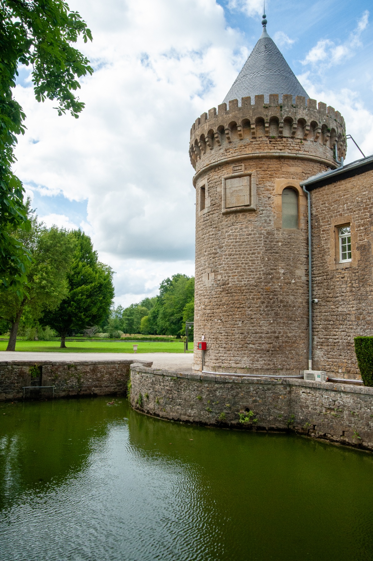 Tour ronde crénelée du château se reflétant dans les douves