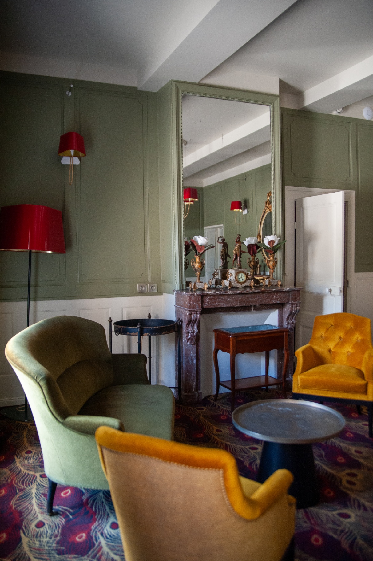 Coin cheminée du salon vert avec miroir, fauteuils jaune moutarde et vert