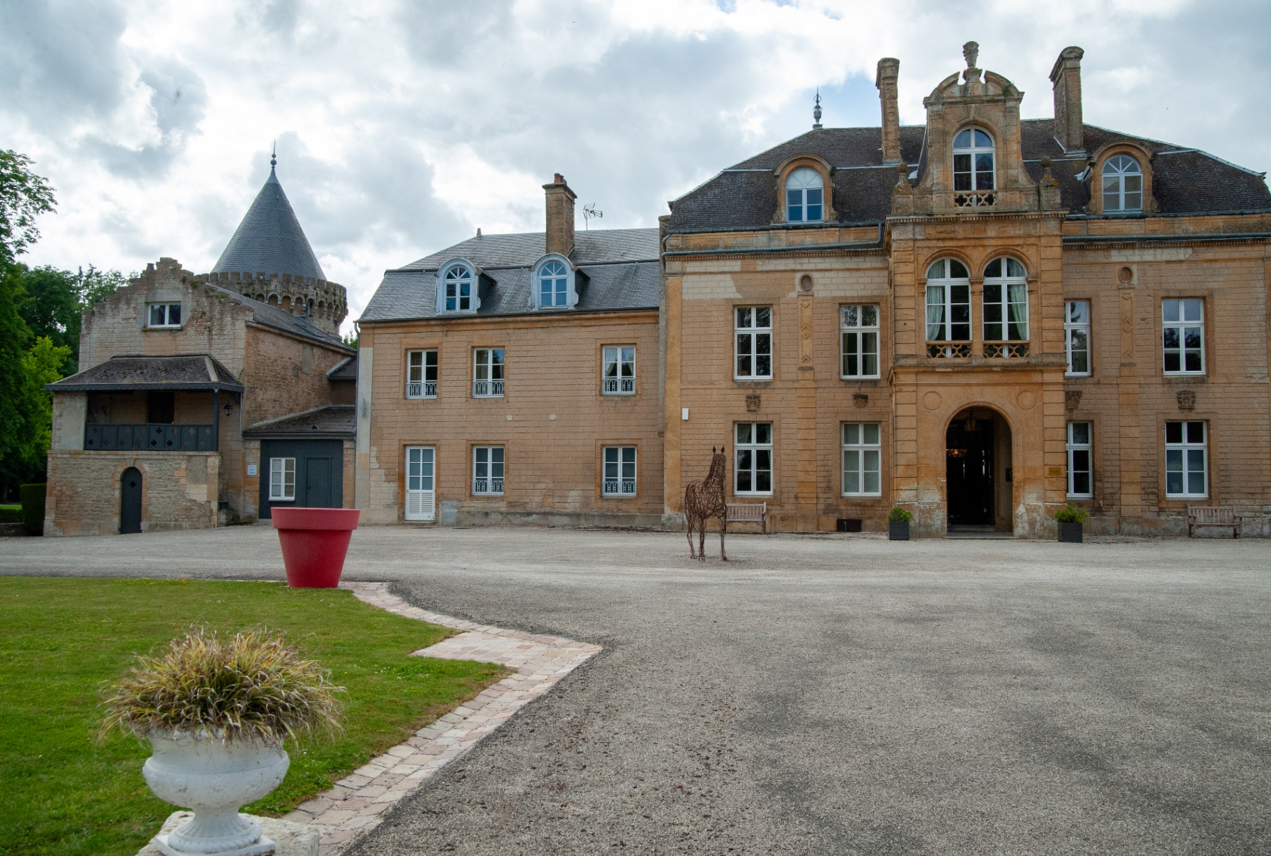 Façade du château avec sa tour médiévale et la cour de gravier